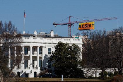 WASHINGTON, DC - JANUARY 25: With the White House in the foreground, protesters unfurl a banner atop a crane at the construction site of the former Washington Post office building, January 25, 2017 in Washington, DC. The protestors are with the Greenpeace organization. (Photo by Drew Angerer/Getty Images)
