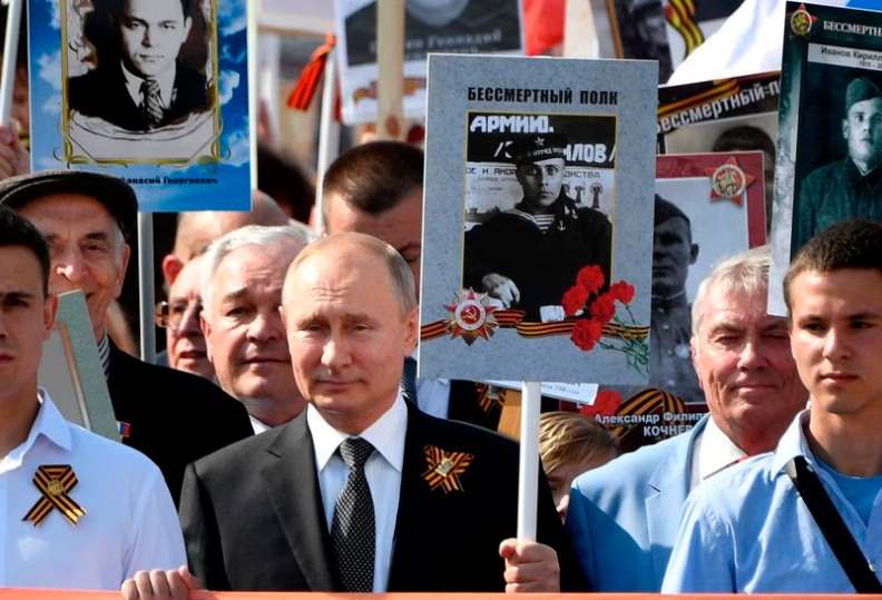 PUTIN ENTRE OTROS CIUDADANOS CON LAS FOTOS DE SUS PADRES VETERANOS