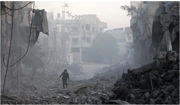 Una persona camina entre los escombros de los edificios destruidos por los ataques aéreos israelíes en el campo de refugiados palestinos de Bureij, en el centro de la Franja de Gaza, el domingo. (EYAD BABA / AFP vía Getty Images)