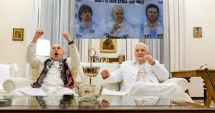 FRANCISCO (JONATHAN PRYCE) CON LA BUFANDA DEL SAN LORENZO Y BENEDICTO, (ANTHONY HOPKINS)  EN LA PELÍCULA DE NETFLIX, VIENDO LA FINAL ARGENTINA-ALEMANIA