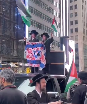 JUDÍOS ANTISIONISTAS ENARBOLAN BANDERAS PALESTINAS JUNTO CON OTRA ISRAELÍ MANCHADA DE SANGRE