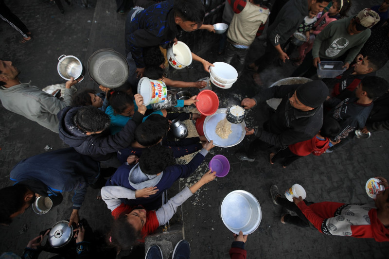 Jóvenes palestinos esperan a que una organización benéfica distribuya alimentos en Rafah, en diciembre de 2024./ Mohammed Zaanoun CTXT