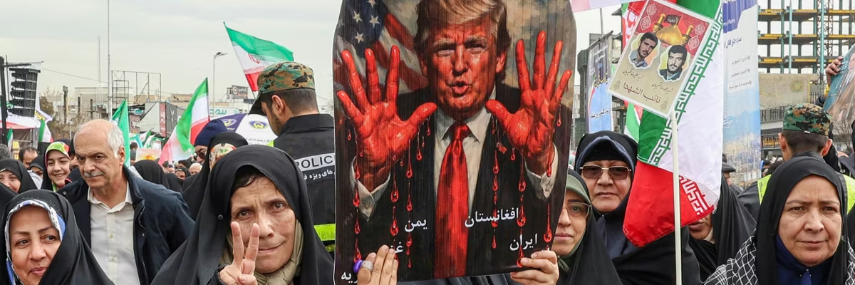Las mujeres marchan con un cartel que representa al presidente estadounidense Donald Trump con las manos ensangrentadas en Teherán el 11 de febrero de 2026, durante una manifestación que conmemora el 47º aniversario de la revolución islámica de 1979. (Foto de AFP vía Getty Images)