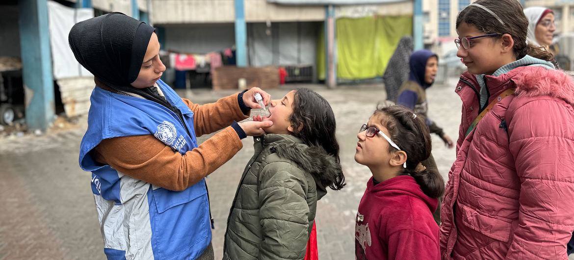 En febrero de 2025, niños de Gaza reciben la vacuna contra la poliomielitis de manos de un trabajador de la ONU. Foto Mohammed Hinnawi -UNRWA